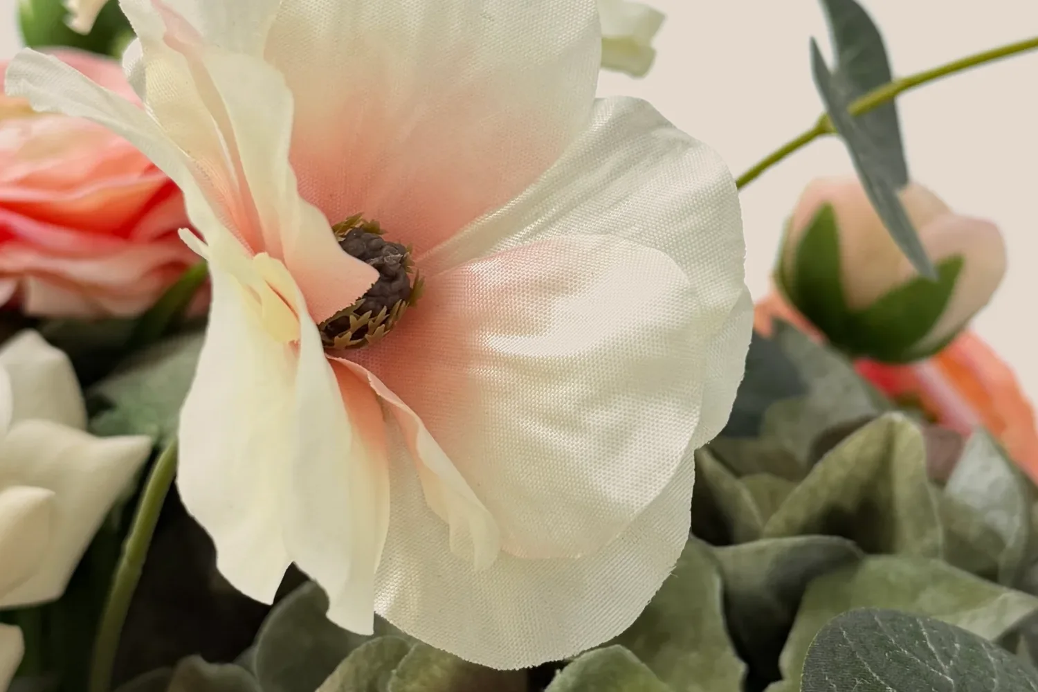 Detail van perzikkleurige en crèmekleurige bloemen met zachtgroen blad.